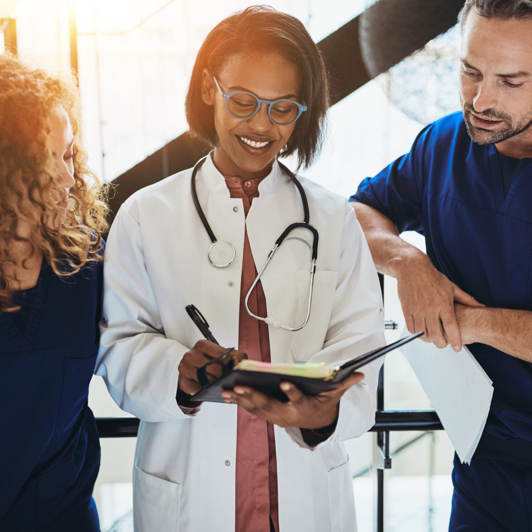 Smiling doctor discussing paperwork with two interns in a hospit