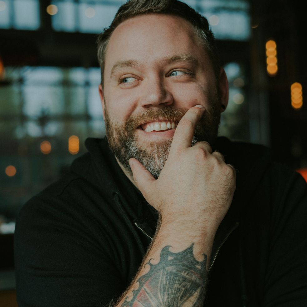 Man with tattoo smiling with his hand on his face